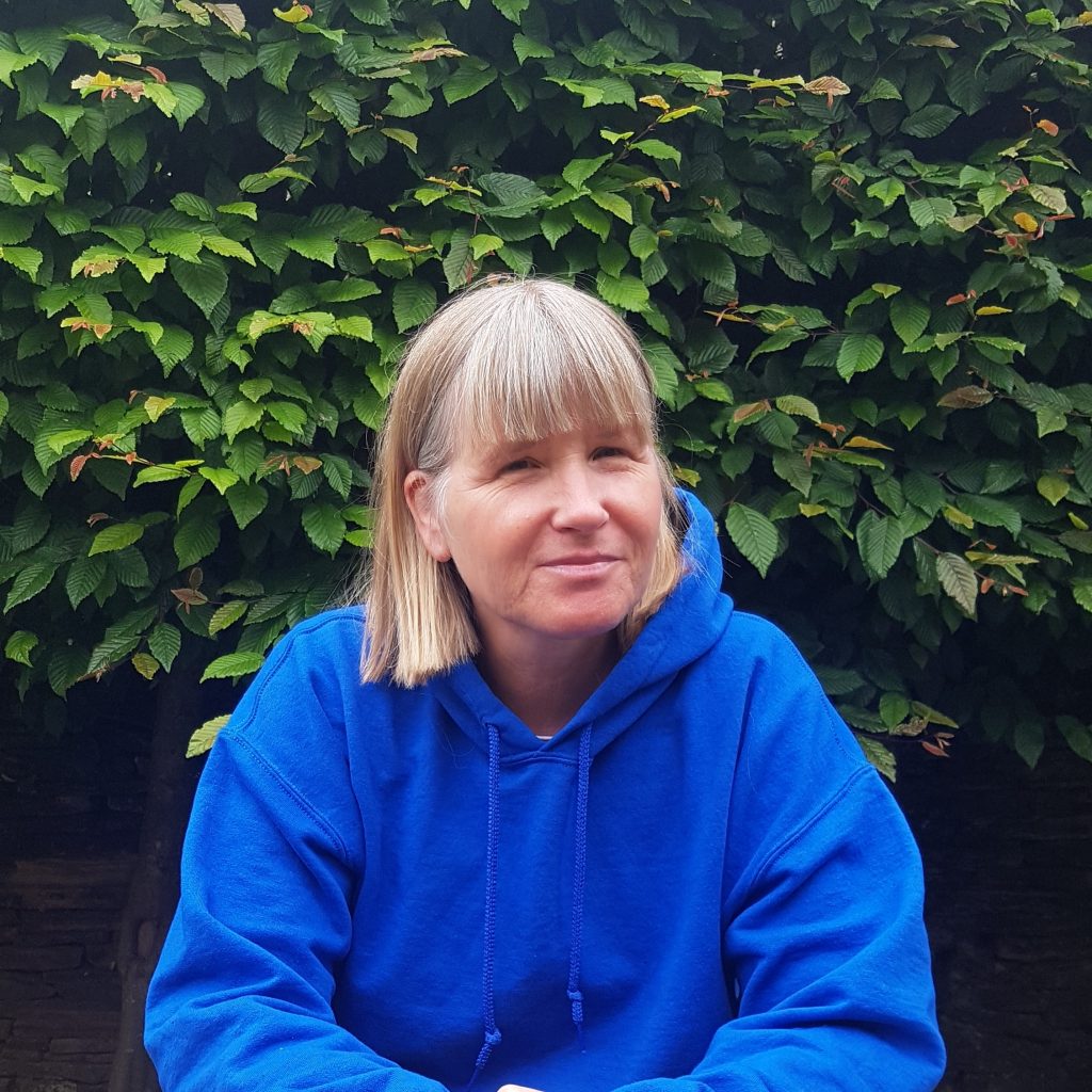 Photograph of Nina Spencer - a white woman with blonde hair wearing a blue hoodie and smiling. 